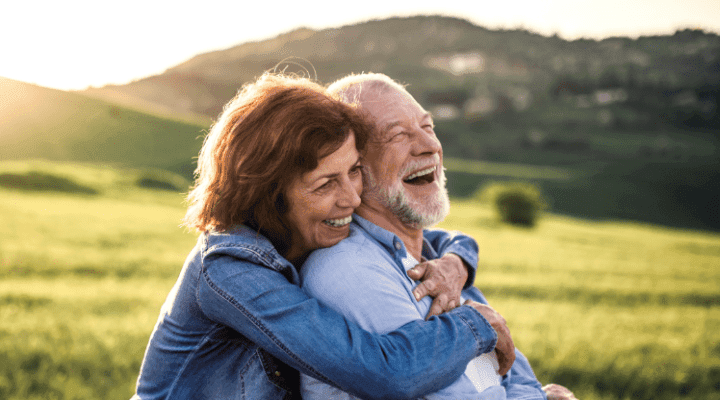 An elderly couple laughing and embracing in the sunlight