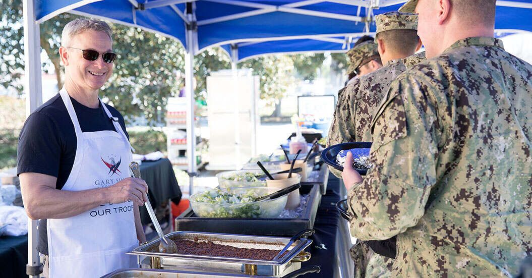 Gary Sinise serves food to military men and women.