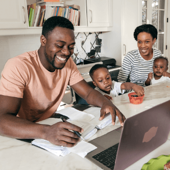 A happy family uses a laptop to check finances and pay bills