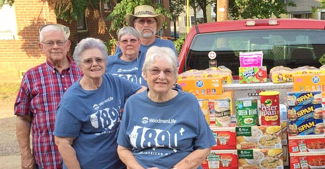 Three women and two men stand by a truck filled with food donations.