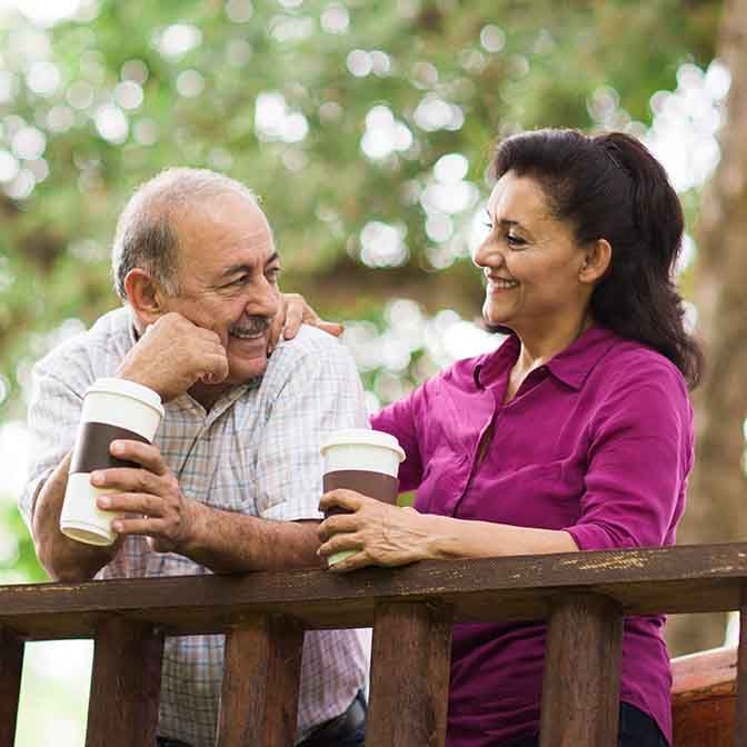 A man and woman enjoy drinking coffee on a balcony