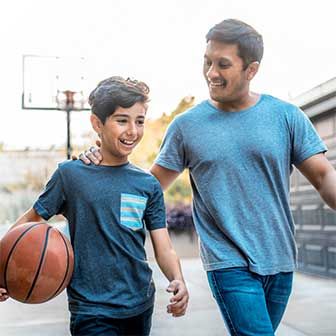 A man and his son playing basketball.