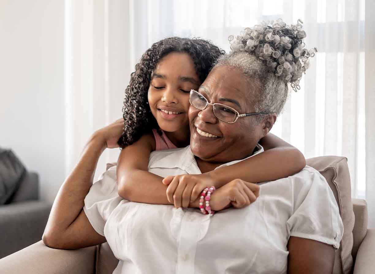 A happy grandmother enjoys a hug from her granddaughter