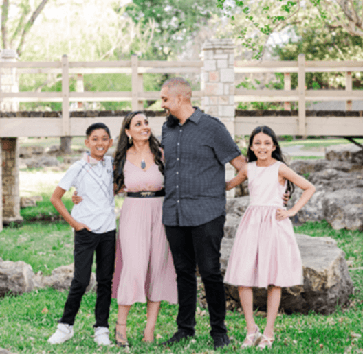 A family smiling and posing for a picture outside.