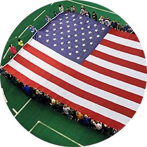A group holds up an American flag at the start of a flag football game.