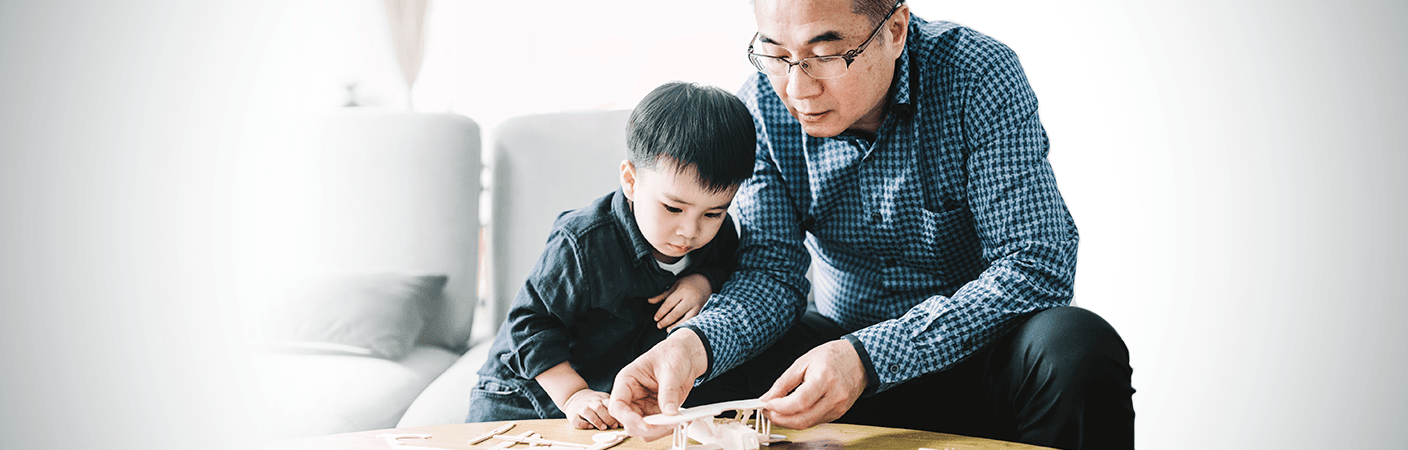 Grandfather assembling model airplane for cute grandson. 