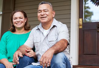 a smiling couple sitting on the steps of their front porch