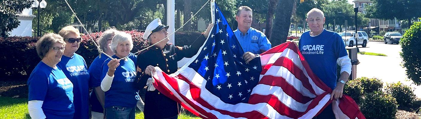 WoodmenLife sales rep and members hoisting an American Flag during a flag presentation.