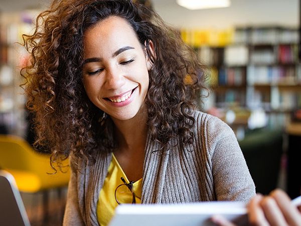 A female entrepreneur looks over a binder and laptop in a library