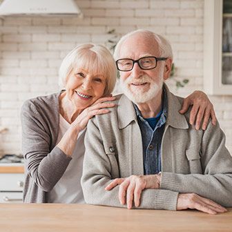 Older white couple sitting together at kitchen island.