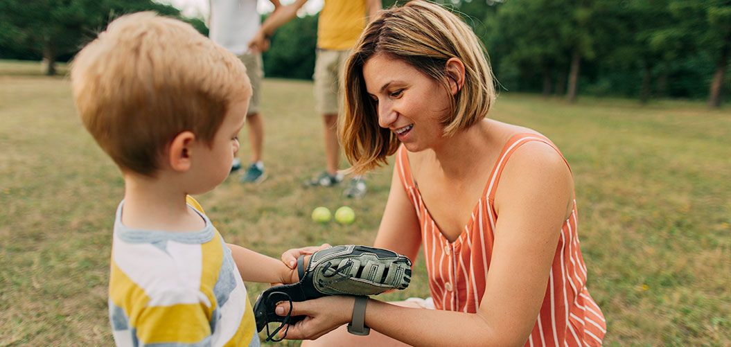 A mom playing baseball outside with her son.